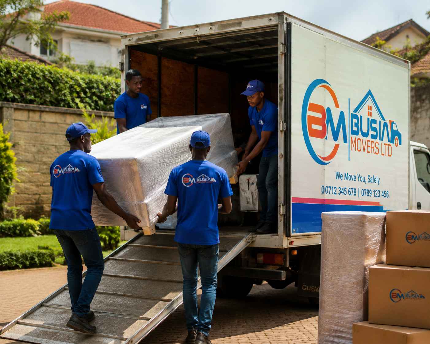 Busia Movers team loading wrapped furniture using truck ramp